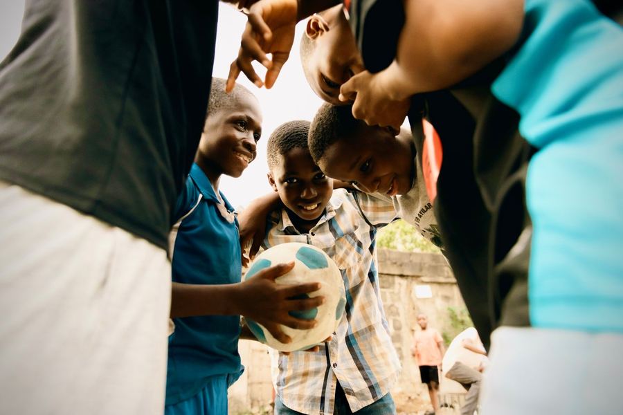 Kids huddled around a football in Lagos