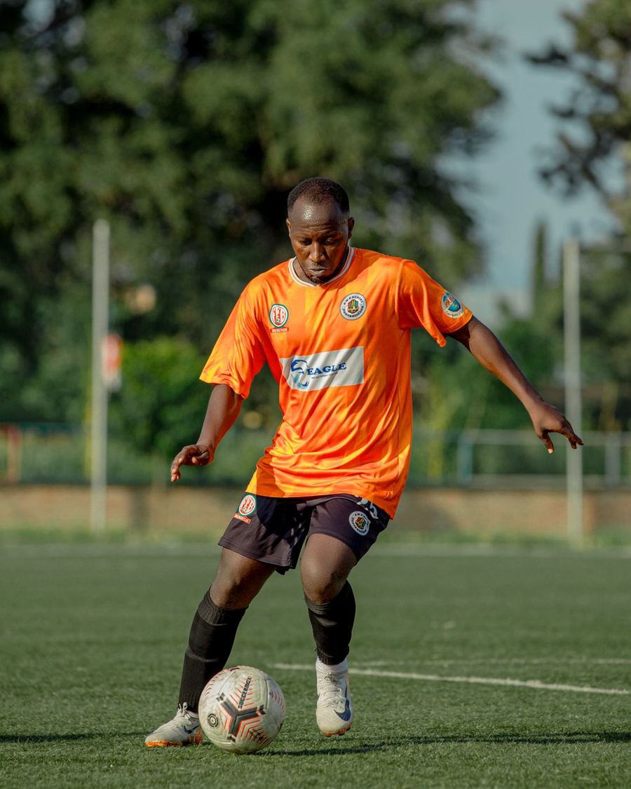A footballer in a national-team shirt holding the ball at the goalpost
